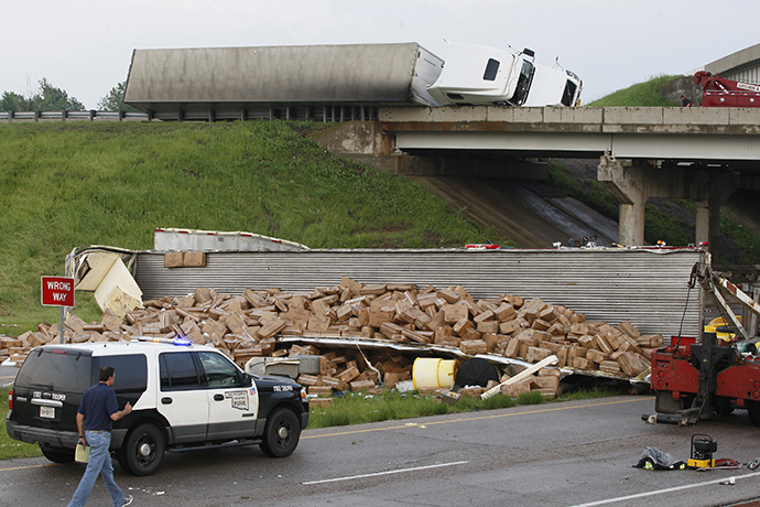 A semi-tractor trailer (top) rests on its side against the guard rails on Interstate 40 as another trailer lies broken open on the road below after falling from I-40, following a tornado strike near Highway 177 north of Shawnee, Oklahoma May 19, 2013. (Reuters / Bill Waugh)
