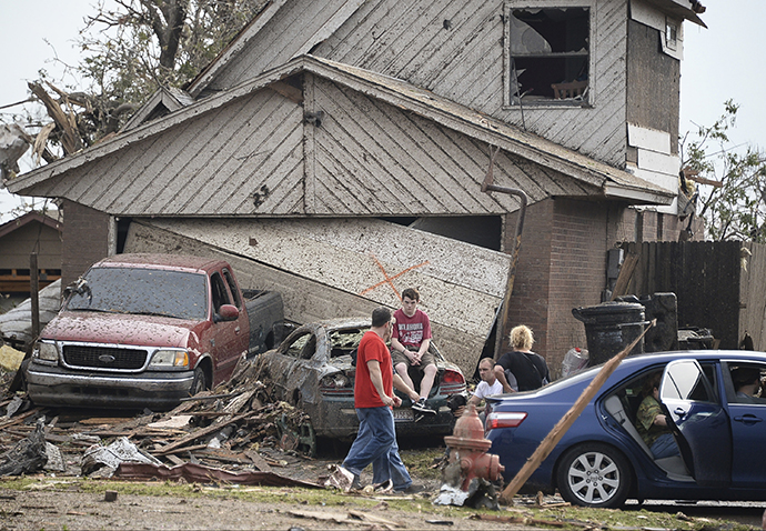People are seen next to a damaged house and vehicles along a street after a huge tornado, in Moore, Oklahoma May 20, 2013. (Reuters / Gene Blevins)