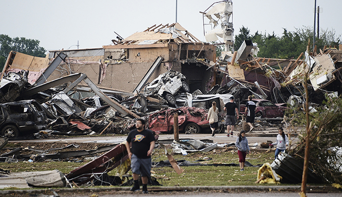 People walk near destroyed buildings and vehicles after a tornado struck Moore, Oklahoma, near Oklahoma City, May 20, 2013. (Reuters / Gene Blevins)