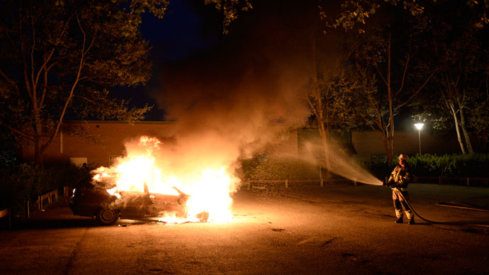 Firemen extinguish a burning car in Kista after youths rioted in few differant suburbs around Stockholm on May 21, 2013.(AFP Photo / Jonathan Nackstrand)