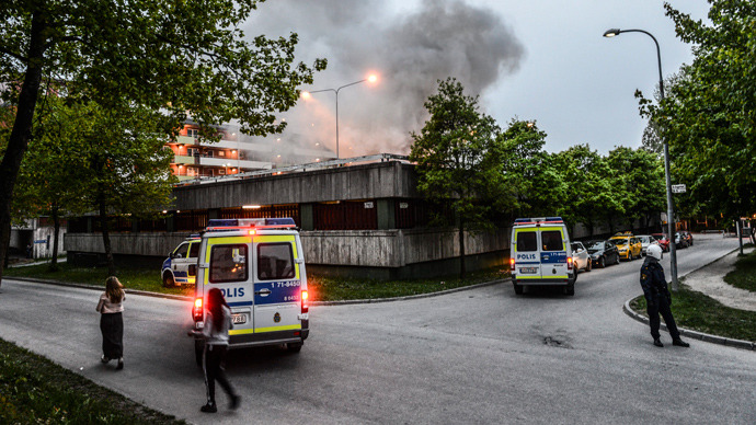 Policemen secure an apartment building after youths rioted in Husby, northern Stockholm on May 20, 2013 (AFP Photo / Fredrik Sandberg / Scanpix Sweden/ Sweden out) 
