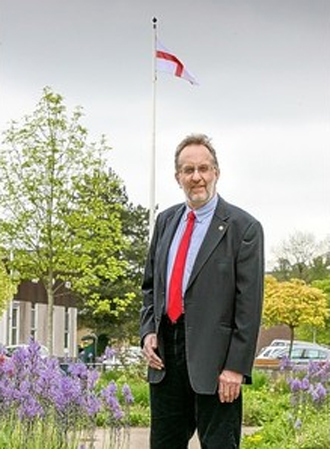 Peter Sas with a flag of St George flying from the flagpole at the Memorial Garden, Radstock (Image from thisisbristol.co.uk)