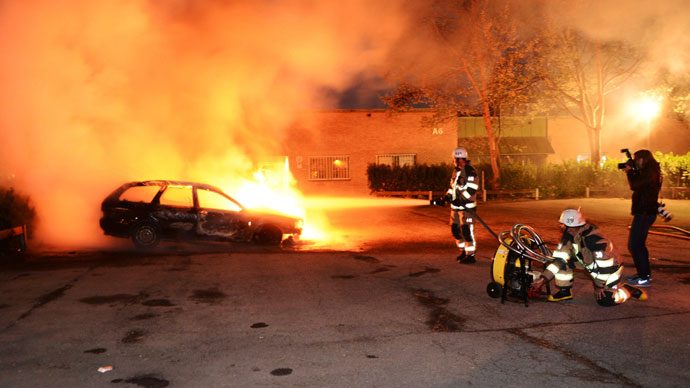 Firefighters extinguish a burning car, following riots in the Stockholm suburb of Kista late May 21, 2013.(Reuters / Fredrik Sandberg)