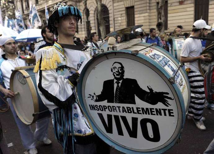 A supporter of Argentine President Cristina Fernandez de Kirchner plays a bass drum displaying a portrait of late Argentine President Nestor Kirchner and reading "Unbearably alive" while arriving to Plaza de Mayo square in Buenos Aires on May 25, 2013. (AFP Photo / Juan Mabromata)