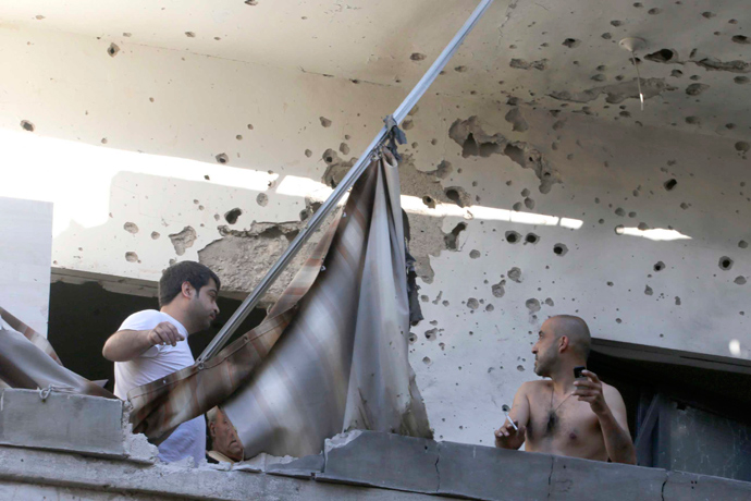 Two men inspect their damage house after two rockets hit their area in a Beirut suburbs May 26, 2013 (Reuters / Mohammed Azakir)