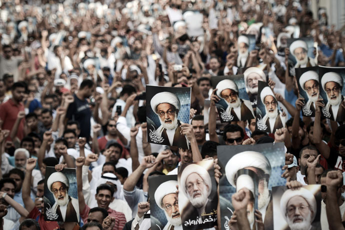 Bahraini protestors shout slogans and hold up pictures of Bahraini top senior shiite cleric, Sheikh Isa Qassim, during an anti-government rally to support Qassim in the village of Diraz, west of the capital Manama, on May 24, 2013.(AFP Photo / Mohammed Al-Shaikh)