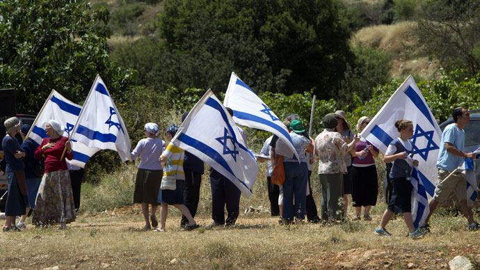 Jewish settlers from the settlements of Gush Etzion and Kiryat Arba wave Israeli flags as they gather on Route 60, mainly used by settlers, near the Palestinian village of Al-Khader in the occupied West Bank on May 24, 2013.(AFP Photo / Ahmad Gharabli)