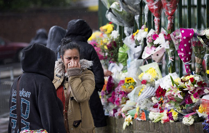 A woman reacts as she looks at floral tributes left at the scene where Drummer Lee Rigby of the 2nd Battalion was killed outside Woolwich Barracks in London on May 24, 2013. (AFP Photo / Justin Tallis)