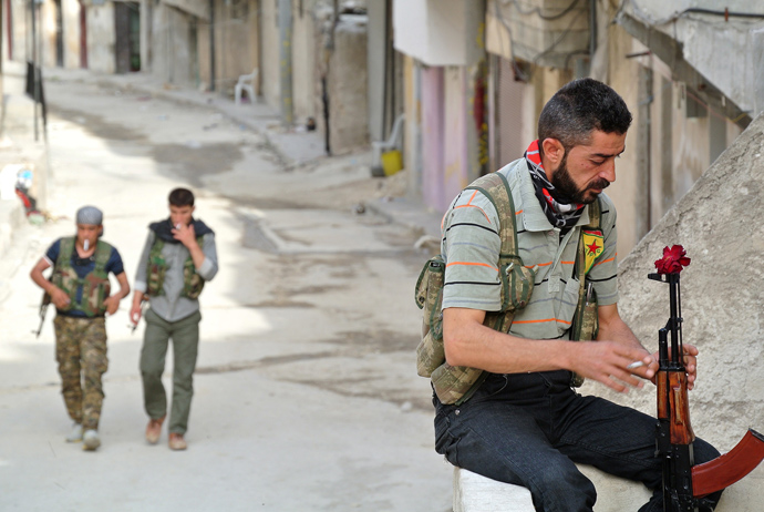 A rebel fighter of the Syrian Kurdish Popular Protection Units (YPG) has a flower in his Russian made 'AK-47' kalashnikov gun as he holds a position in the Sheikh Maqsoud neighbourhood in the Syrian city of Aleppo on May 9, 2013 (AFP Photo / Str) 