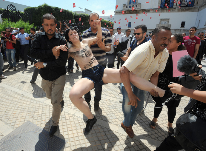 One of three topless activists from the Femen feminist group, is arrested by a plainclothed policemen as they demonstrate in front of the justice Palace in Tunis, on May 29, 2013 (AFP Photo / Fethi Belaid) 