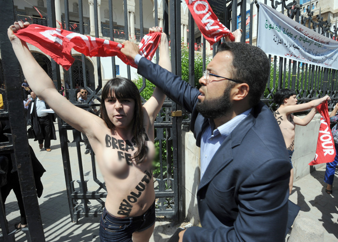 A lawyer tries to snatch a banner being held by one of three activists from the Femen feminist group, as they demonstrate in front of the justice Palace in Tunis, on May 29, 2013, before being arrested (AFP Photo / Fethi Belaid) 