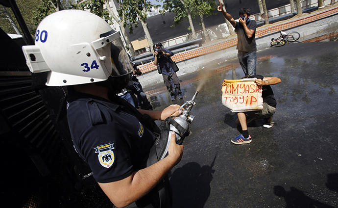 A Turkish riot policeman uses tear gas as a demonstrator holds a banner which reads that, "Chemical Tayyip", referring to Prime Minister Tayyip Erdogan, during a protest against the destruction of trees in a park brought about by a pedestrian project, in Taksim Square in central Istanbul May 31, 2013. (Reuters / Murad Sezer)
