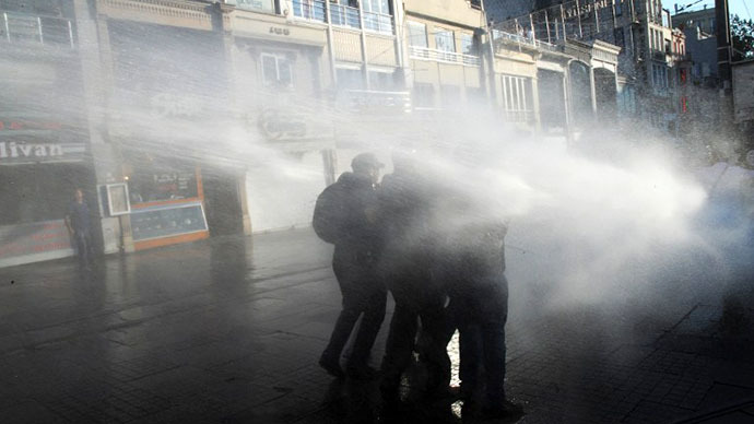 Protesters take cover from a water cannon during clashes with police on Istiklal Avenue in Istanbul on July 8, 2013. (AFP Photo / Bulent Kilic)