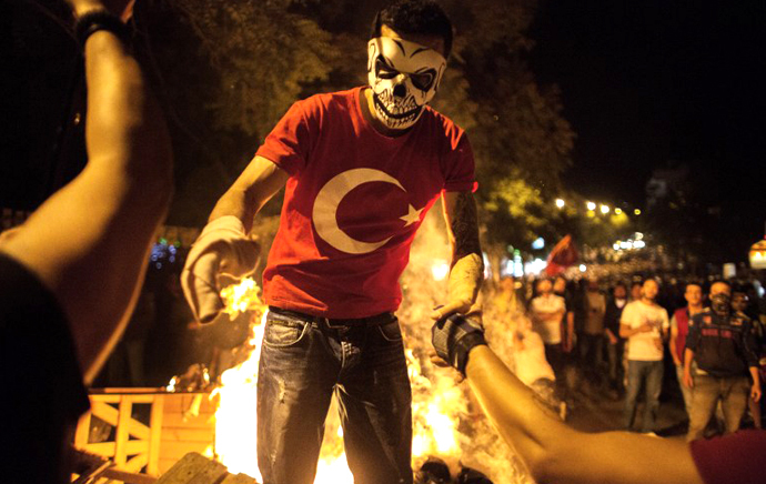 A masked protester is helped during clashes with Turkish riot police June 12, 2013 in central Ankara. (AFP Photo / Marco Longari)