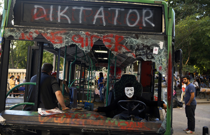 A protester sits inside a damaged bus used by anti-government protesters as a barricade in Istanbul's Taksim square June 10, 2013. (Reuters / Yannis Behrakis)