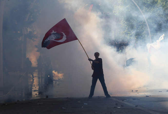 Tear gas surrounds a protestor holding a Turkish flag with a portrait of the founder of modern Turkey Mustafa Kemal Ataturk as he takes part in a demonstration in support of protests in Istanbul and against the Turkish Prime Minister and his ruling Justice and Development Party (AKP), in Ankara, on June 1, 2013 (AFP Photo / Adem Altan)