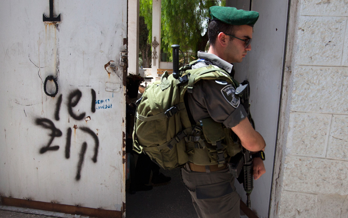 An Israeli border guard stands next to anti-Christian graffiti reading in Hebrew, "Jesus is monkey" that was daubed on the Church of the Dormition, one of Jerusalem's leading pilgrimage sites, early on May 31, 2013 (AFP Photo / Ahmad Gharabli) 