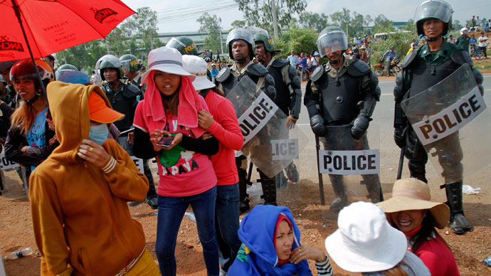 Garment workers stand near police officers during a protest in front of a factory owned by Sabrina (Cambodia) Garment Manufacturing in Kampong Speu province, west of the capital Phnom Penh June 3, 2013.(Reuters / Samrang Pring)