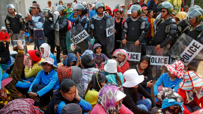 Garment workers sit beside police officers during a protest in front of a factory owned by Sabrina (Cambodia) Garment Manufacturing in Kampong Speu province, west of the capital Phnom Penh June 3, 2013.(Reuters / Samrang Pring)