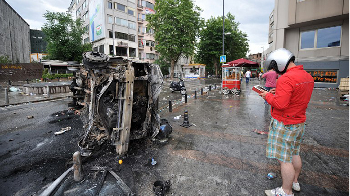A protestor takes a photo of a burnt Turkish TV vehicle in Taksim square on June 2, 2013, after the clashes. (AFP Photo / Ozan Kose)