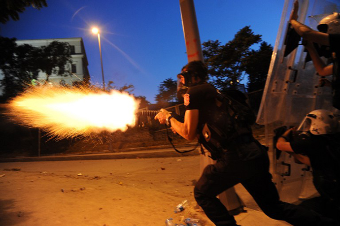 Turkish riot police officer fires tear gas during clashes with protestors between Taksim and Besiktas in Istanbul on June 3, 2013 during a demonstration against the demolition of the park. (AFP Photo / Bulent Kilic)