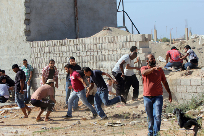 Libyan protesters protect themselves behind a wall during clashes between demonstrators and troops of the Libyan Shield Forces (LSF), a coalition of militias, following a demonstration outside the LSF office in the northern city of Benghazi on June 8, 2013 (AFP Photo / Abdullah Doma)