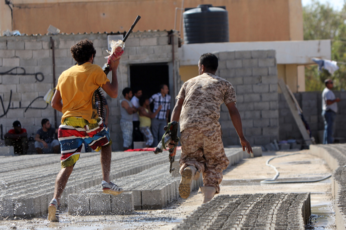 Members of Libyan security forces run away holding weapons during clashes between protesters and troops of the Libyan Shield Forces (LSF), a coalition of militias, following a demonstration outside the LSF office in the northern city of Benghazi on June 8, 2013 (AFP Photo / Abdullah Doma)