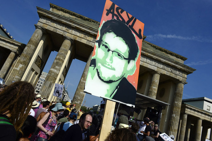 Demonstrators hold up a placard in support of former US agent of the National Security Agency, Edward Snowden in front of Berlin's landmark Brandenburg Gate as they take part in a protest against the US National Security Agency (NSA) collecting German emails, online chats and phone calls and sharing some of it with the country's intelligence services in Berlin on July 27, 2013. (AFP Photo)