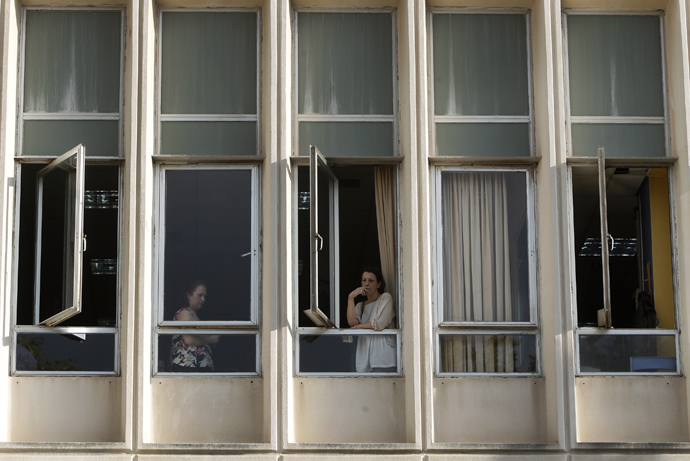 An employee smokes a cigarette at a window of Greek state television ERT headquarters after the government's announcement that it will shut down the broadcaster in Athens June 11, 2013. (Reuters / John Kolesidis)