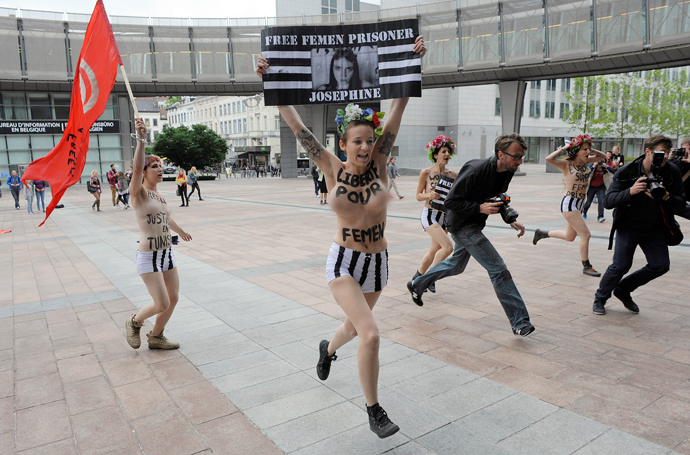 Members of the women's topless protest group Femen hold banners during a protest in front of the European Union Parliament on June 12, 2013 in Brussels, to support a detained Tunisian activist and four other Femen, two French and one German, arrested in Tunis for baring their breasts outside the main courthouse on May 29, in solidarity with a Tunisian activist who had been arrested 10 days earlier (AFP Photo / John Thys)