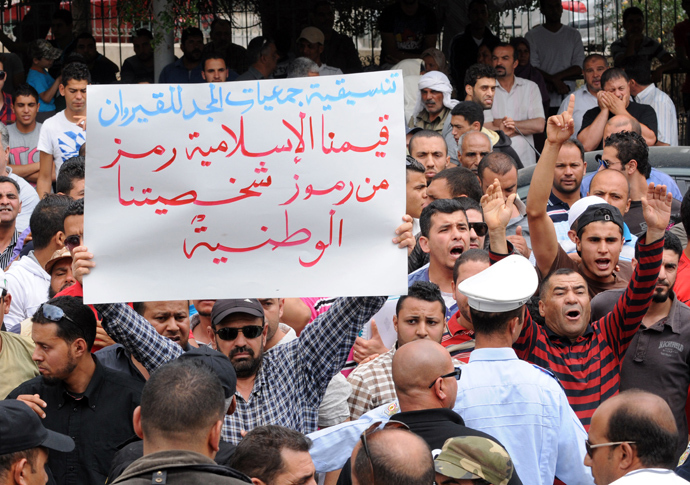 Tunisian protestors hold a a placard praising Islamic values as they shout slogans outside the courthouse where Amina Sboui, the Tunisian member of the Ukrainian feminist group Femen, is being put on trial charged with illegal possession of pepper spray on May 30, 2013 in the central city of Kairouan (AFP Photo / Salah Habibi)