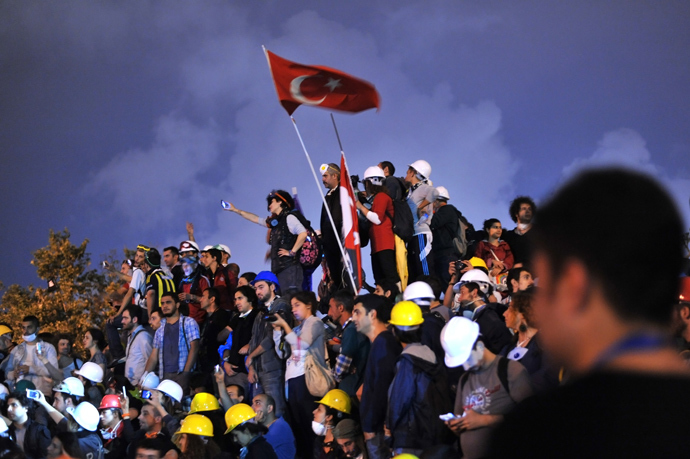 Anti-goverment protestors unfurl the Turkish national flag in Taksim Gezi Park on June 13, 2013 in Istanbul after a large clean-up operation removed all evidence of unrest, the square cleared of of stray tear gas cannisters, anti-Erdogan banners and makeshift barricades (AFP Photo / Ozan Kose)