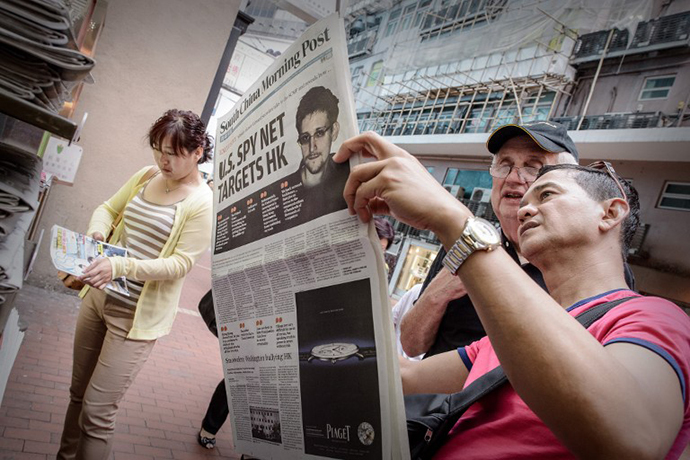 Two men read an edition of the South China Morning Post carrying the story of former US spy Edward Snowden on its front page in Hong Kong on June 13, 2013. (AFP Photo / Philippe Lopez)