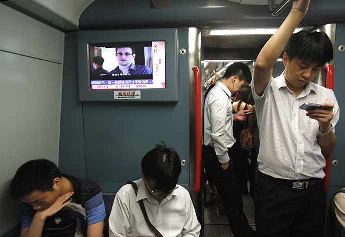 Passengers stand beside a TV screen broadcasting news of Edward Snowden, a contractor at the National Security Agency (NSA), on a train in Hong Kong June 13, 2013. (Reuters / Bobby Yip)