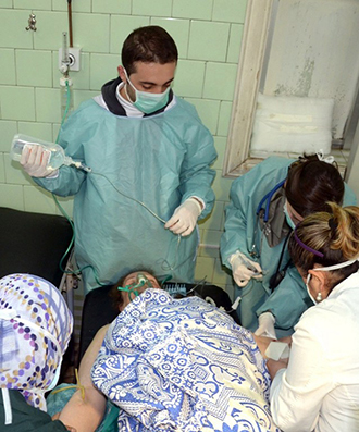 Medics check a woman at a hospital in the northern Aleppo province, as Syria's government accused rebel forces of using chemical weapons for the first time on March 19, 2013. (AFP Photo / SANA)