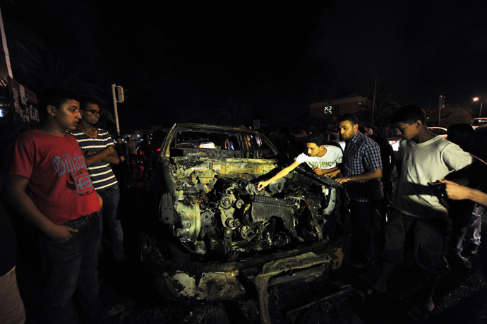 Youths look into the engine of a burnt-out vehicle used by the Libyan Army's First Infantry Brigade, one of two military vehicles set on fire by protesters, in Benghazi June 14, 2013. (Reuters/Esam Al-Fetori)