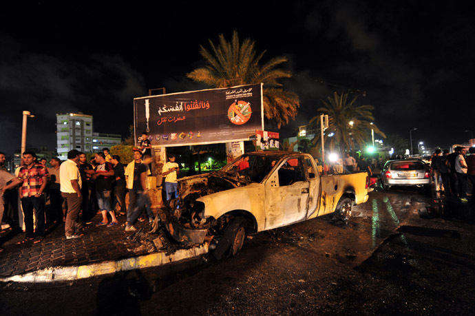 People gather around a burnt-out vehicle used by the Libyan Army's First Infantry Brigade, one of two military vehicles set on fire by protesters, in Benghazi June 14, 2013. (Reuters/Esam Al-Fetori)