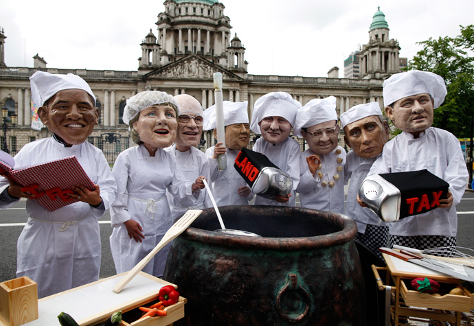 Oxfam charity volunteers wear masks depicting the G8 leaders around a large cauldron during a photo call to draw attention to the issue of world hunger outside City Hall in Belfast, Northern Ireland, on June 16, 2013 (AFP Photo / Peter Muhly)