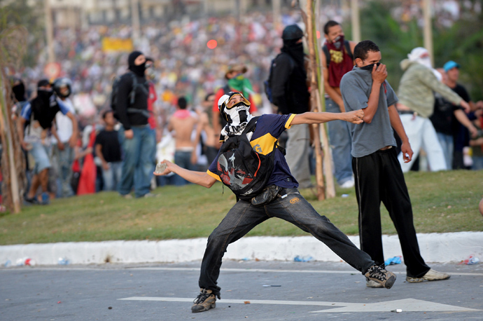 A demonstrator throws a stone against anti riot policemen during a protest against corruption and price hikes near Mineirao stadium in Belo Horizonte, Brazil on June 22, 2013 (AFP Photo / Nelson Almeida)