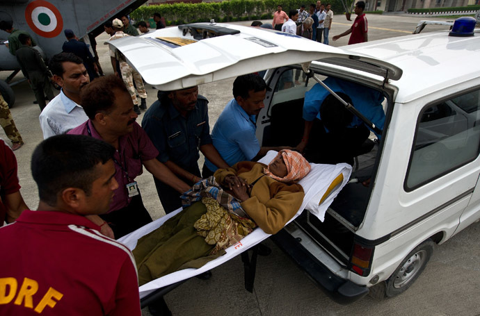 Indian disaster relief personnel assist an elderly woman into an ambulance after being evacuated from flood-hit areas at the Jolly Grant Airport in Dehradun, state capital of Uttarakhand on June 21, 2013. (AFP Photo)