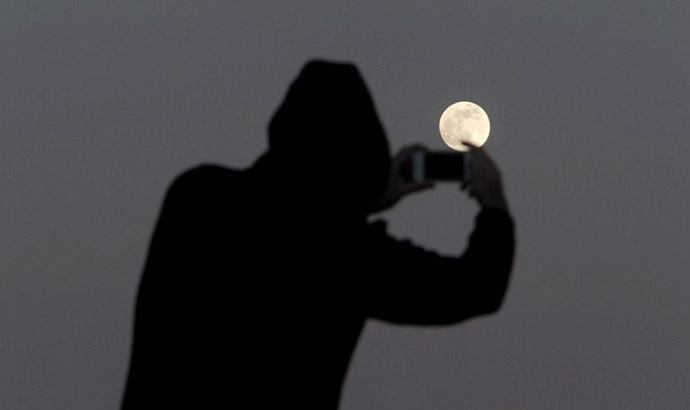 A man takes pictures of the full moon on the Spanish Canary island of Tenerife on June 22, 2013. (AFP Photo / Desiree Martin)
