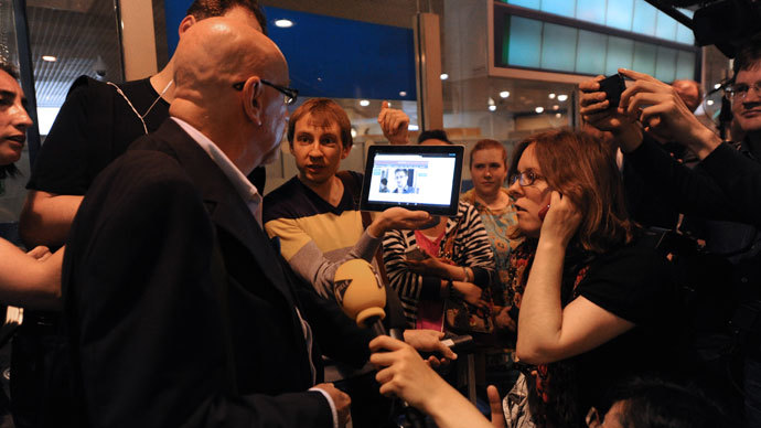 A journalist shows to a passenger a picture of former US spy Edward Snowden on a tablet, at the arrival gate of the Moscow Sheremetevo airport on June 23, 2013. Snowden arrived on June 23, 2013.(AFP Photo / Vasily Maximov)