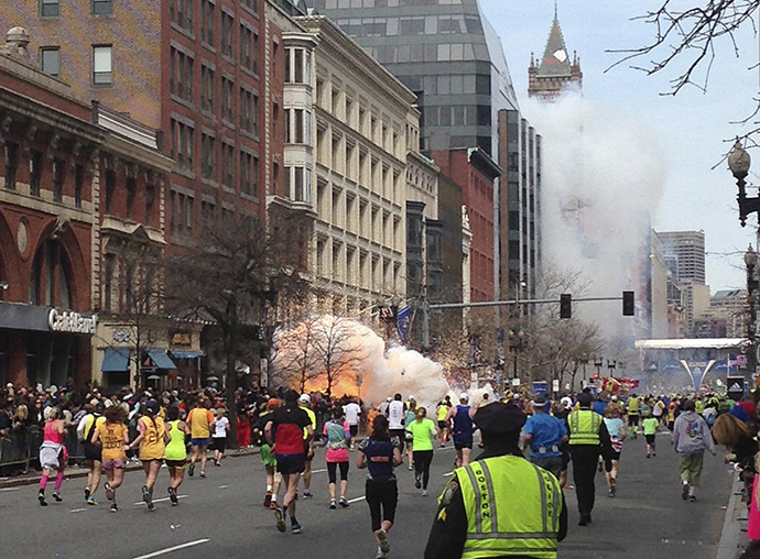 Runners continue to run towards the finish line of the Boston Marathon as an explosion erupts near the finish line of the race in Boston, Massachusetts, April 15, 2013. (Reuters / Dan Lampariello)