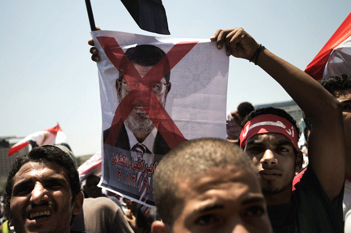 An Egyptian opposition supporter holds a crossed-out picture of President Mohammed Morsi (AFP Photo / Gianluigi Guercia)