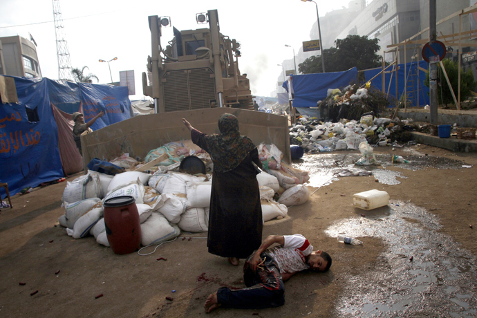 An Egyptian woman tries to stop a military bulldozer from hurting a wounded youth during clashes that broke out as Egyptian security forces moved in to disperse supporters of Egypt's deposed president Mohamed Morsi in eastern Cairo on August 14, 2013 (AFP Photo / Mohammed Abdel Moneim) 