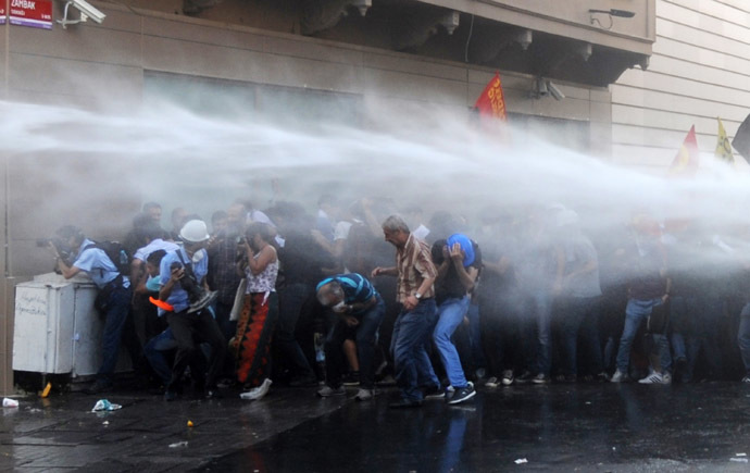 Protesters take cover from a water cannon during clashes with police on Istiklal Avenue in Istanbul on July 6, 2013. (AFP Photo/Bulent Kilic)