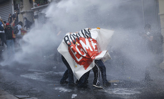 Demonstrators hold a banner reading, "Don't bow down", as riot police use water cannon to disperse them during a protest in central Istanbul July 6, 2013. (Reuters/Murad Sezer)