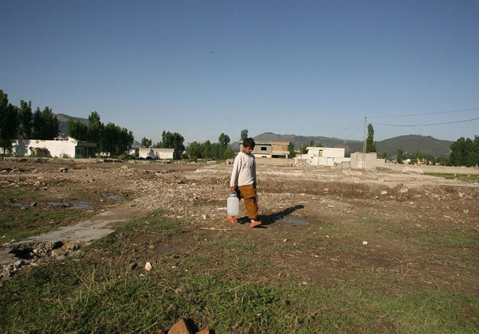 A Pakistani boy carries water cans at the site of the demolished compound of slain Al-Qaeda leader Osama bin Laden in northern Abbottabad on May 2, 2012. (AFP Photo / Sajjad Qayyum)