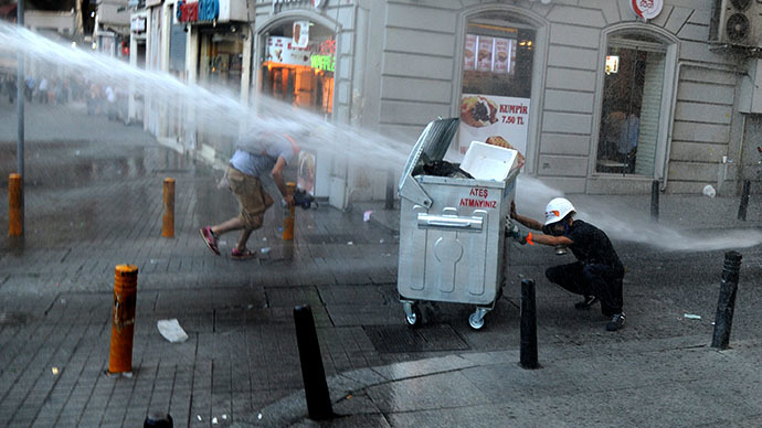 A protestor take cover from water cannon during clashes with police officers on Istiklal avenue, in Istanbul on July 8, 2013. (AFP Photo / Bulent Kilic)