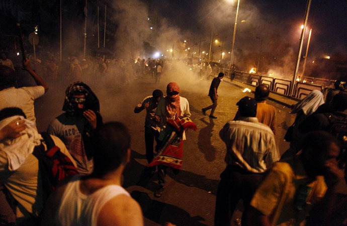 People run for cover as security forces fire tear gas after shooting to disperse Islamist supporters of ousted president Mohamed Morsi outside the Republican Guard headquarters in Cairo in the early hours of July 8, 2013. (AFP Photo / Mahmoud Khaled)